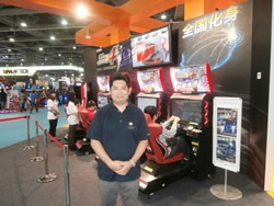 Bandai Namco’s Osama Sakamoto stands with his company’s Midnight Maximum Tune 4 display