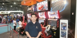 Bandai Namco’s Osama Sakamoto stands with his company’s Midnight Maximum Tune 4 display